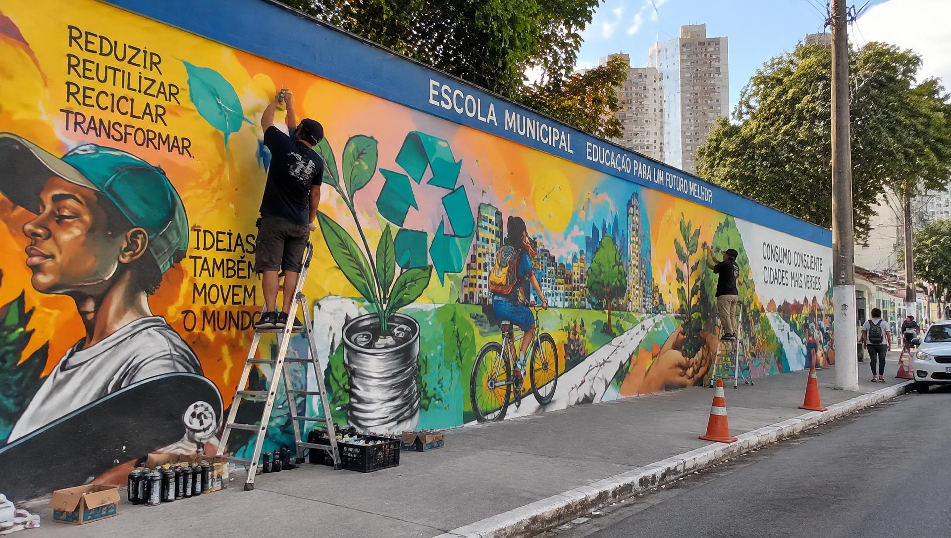 Artistas pintando mural no muro de uma escola